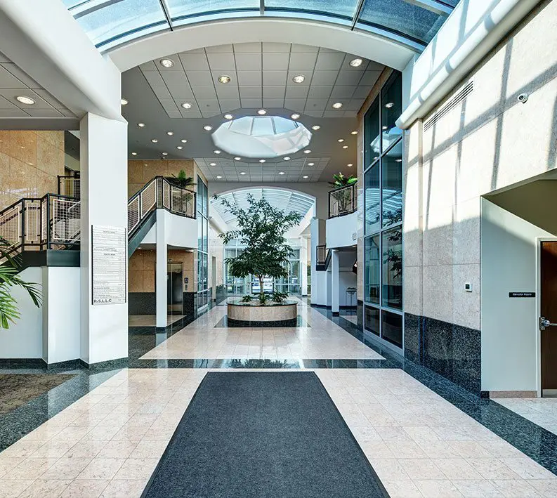 A large hallway with glass walls and a black rug.