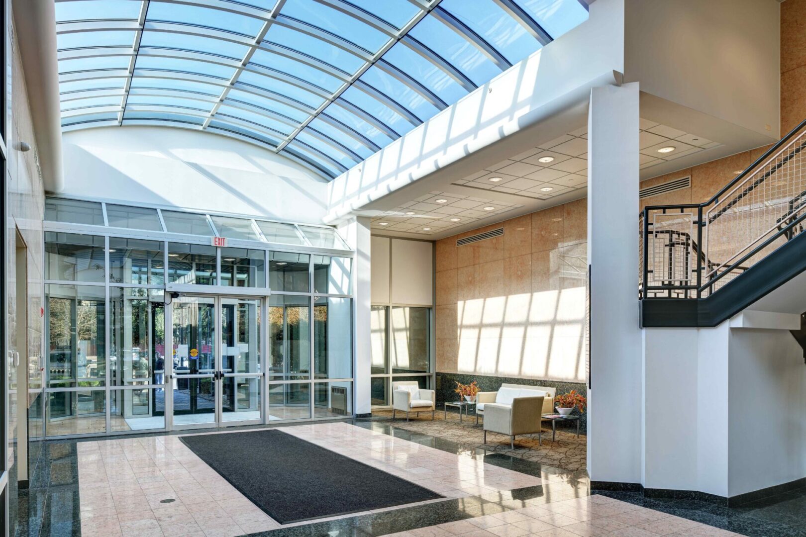 A lobby with glass walls and a black rug.