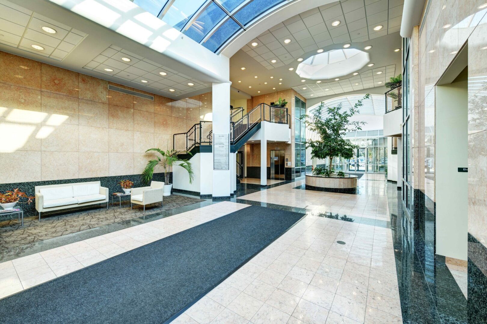 A large lobby with stairs and a glass ceiling.