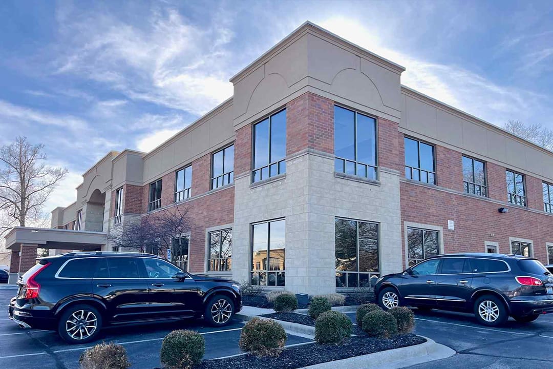 Two cars parked in front of a building with windows.