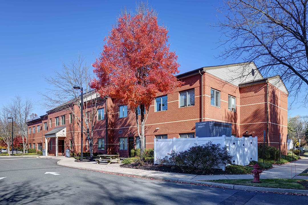 A red brick building with a tree in front of it.